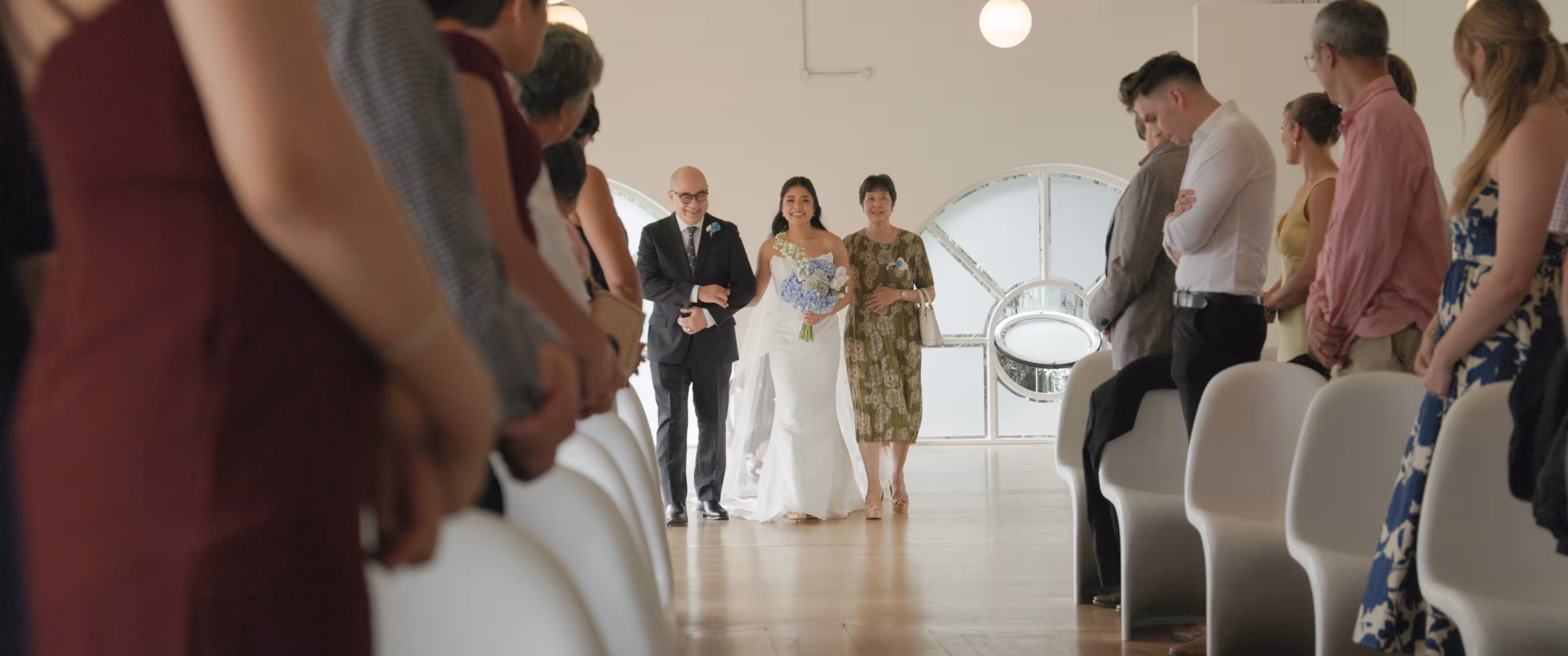 Jennifer walking down the aisle at Mantells Tamaki Drive with light pouring in from the Mission Bay waterfront