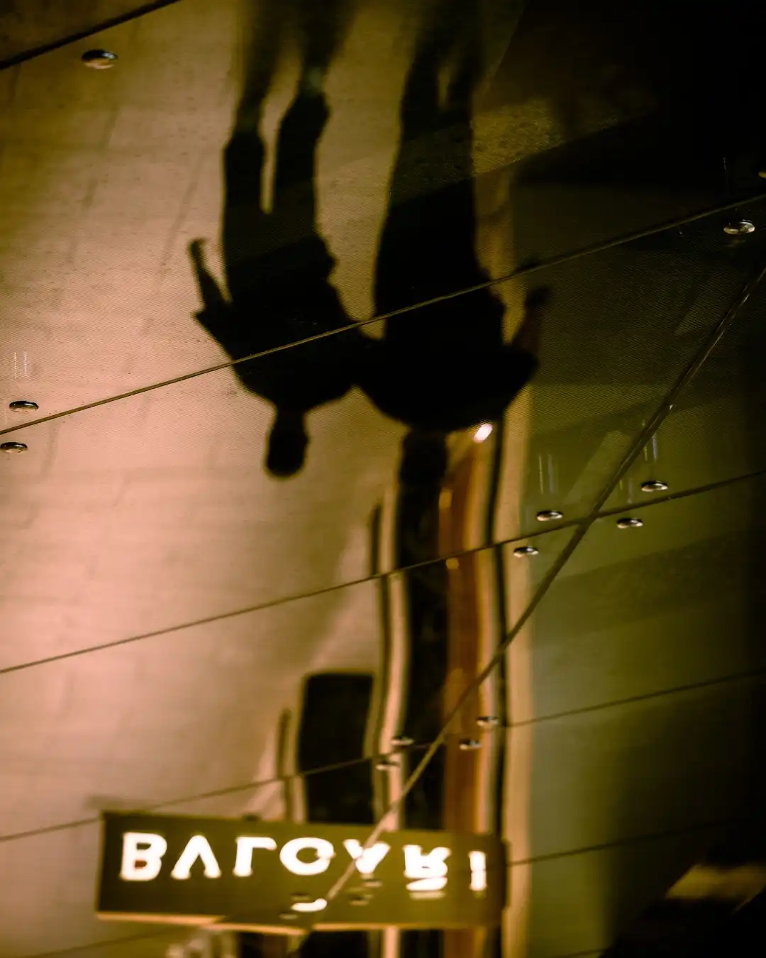 Two silhouettes reflected in a gold mirrored ceiling.