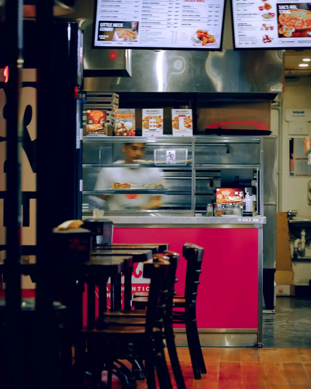 Takeaway shop interior with staff in motion behind the counter.