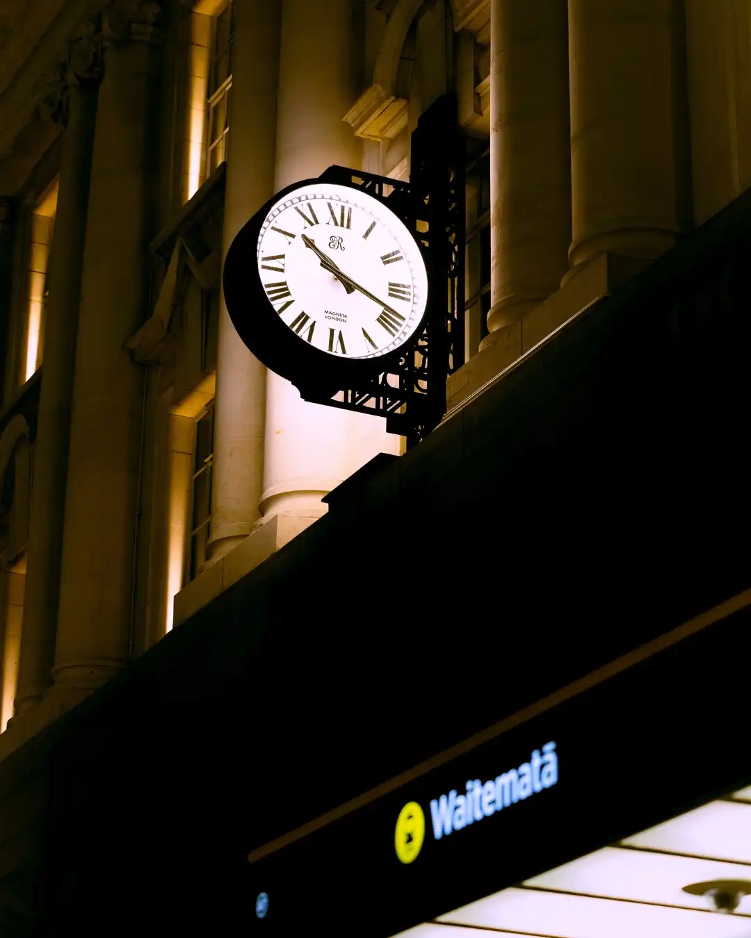 Illuminated clock on a historic building at night.