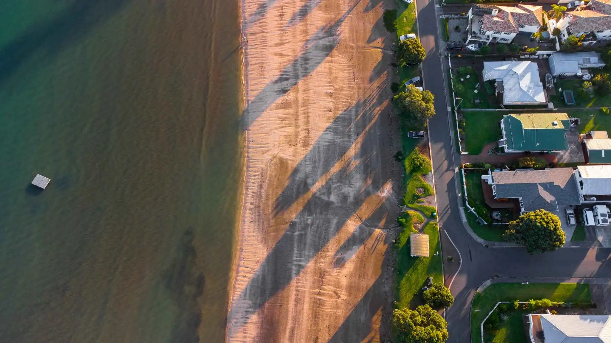 Aerial view of Arkles Bay beach at sunset.