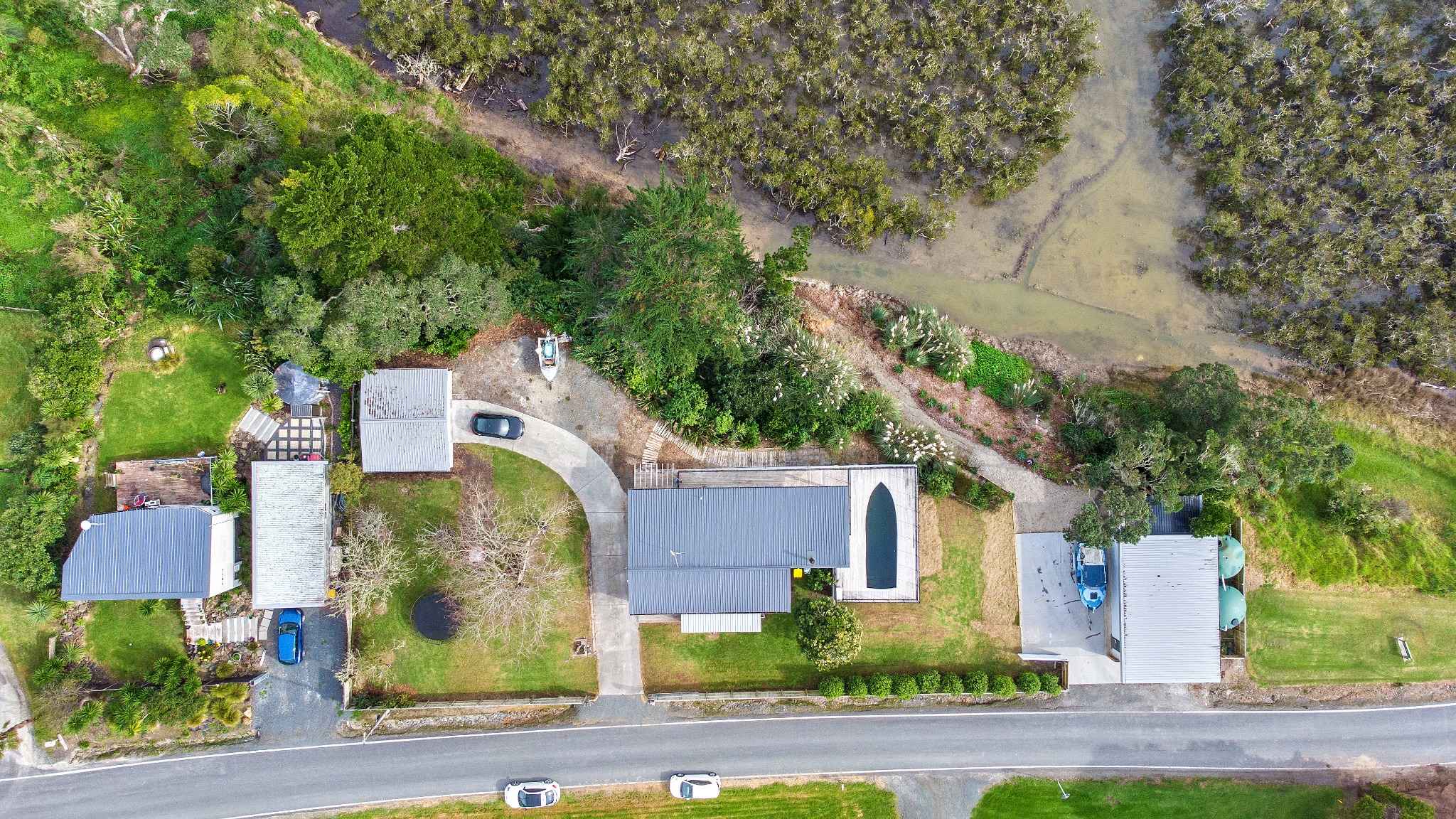 Bird’s-eye drone photo showing residential property boundaries marked, surrounded by greenery and neighboring houses.