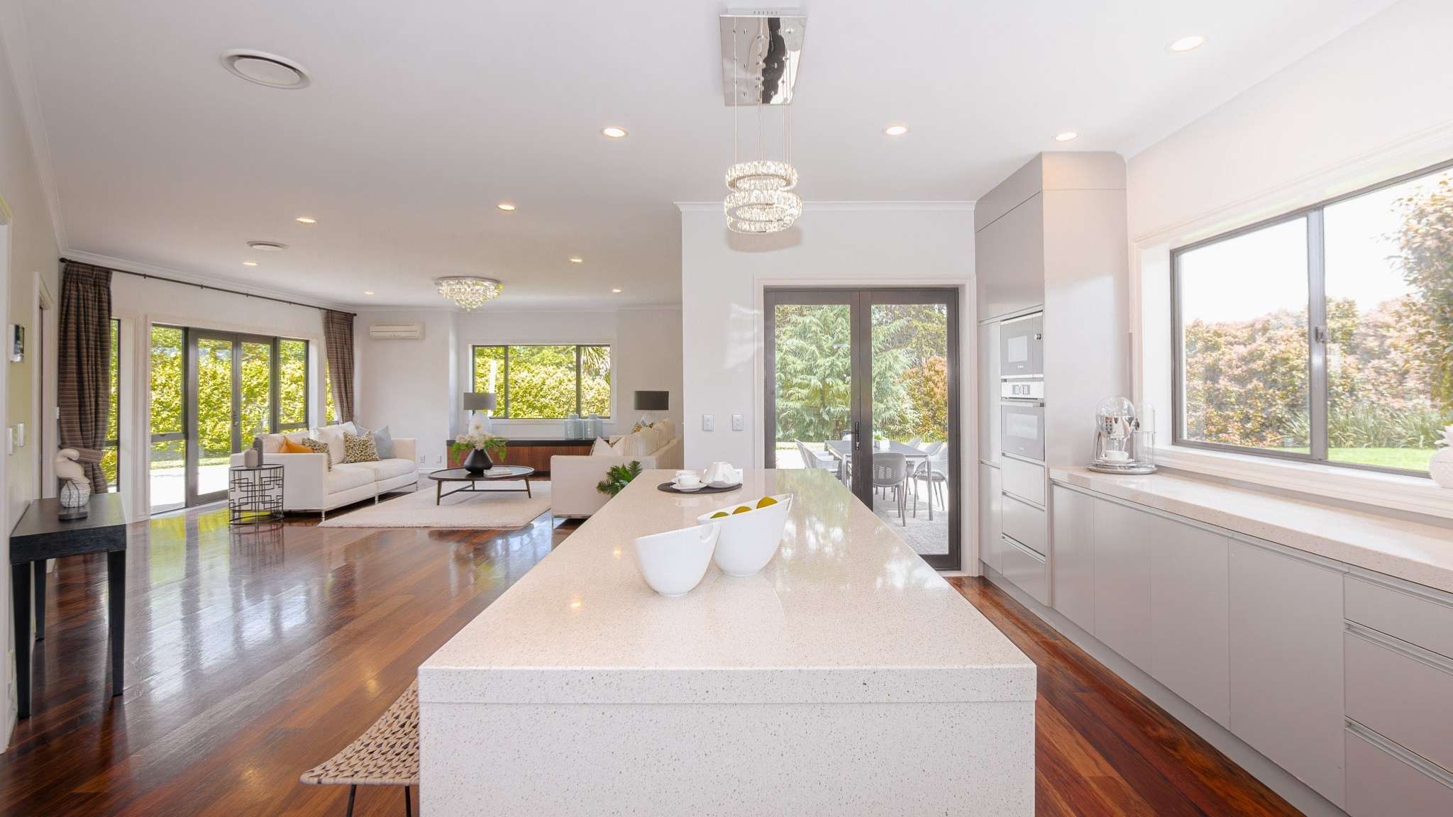 Contemporary open-plan kitchen and dining room with island bench, pendant lighting, and timber flooring.